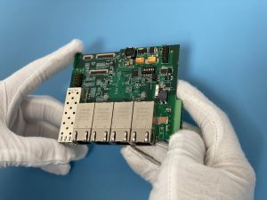 Inspecting a printed circuit boards using gloved hands on a blue electrostatic discharge mat