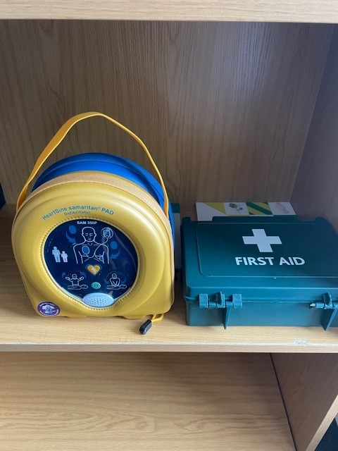 A defibrillator next to a first aid kit at the Photronix office.